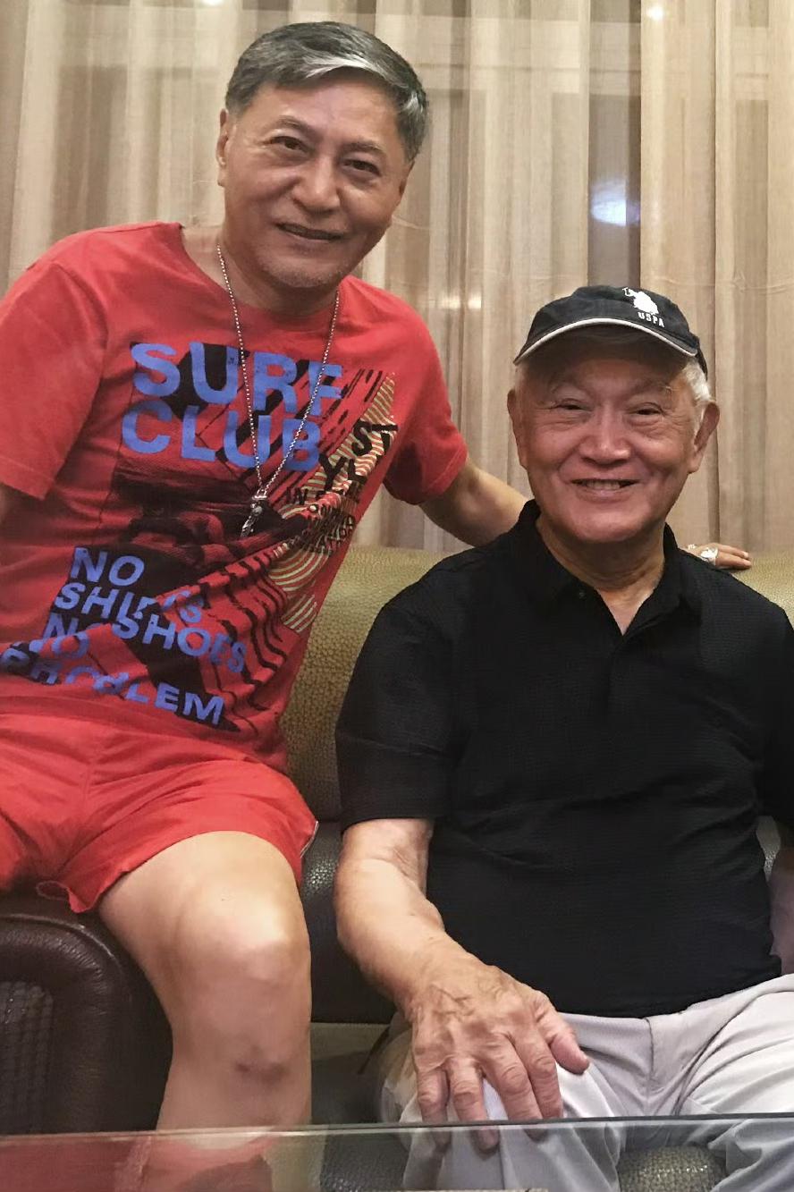 2024年，牛犇（本名张学景）和儿子王侃的合影，身旁一身红色休闲套装、手臂轻搭父