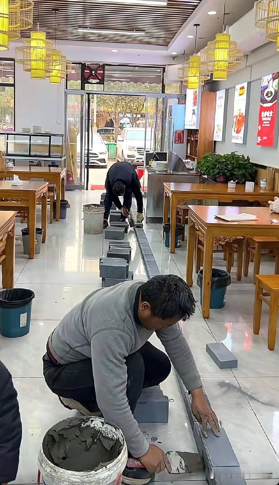 这是两夫妻分家了，这餐馆是要“一分为二”小吃店里俩师傅蹲地上铺青砖，一人占