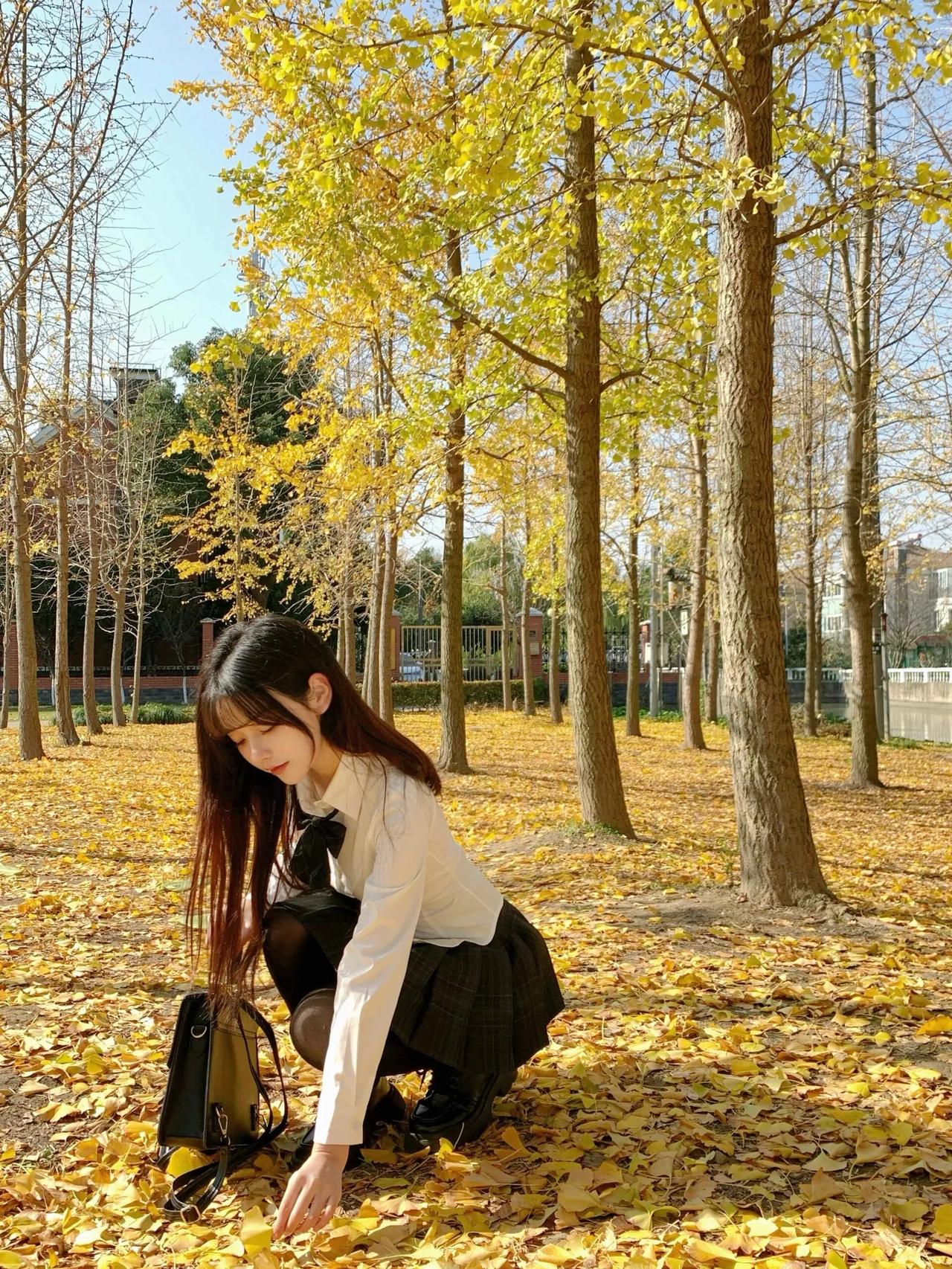 秋日校园，落叶纷飞，少女拾起一片，感受季节的美好。