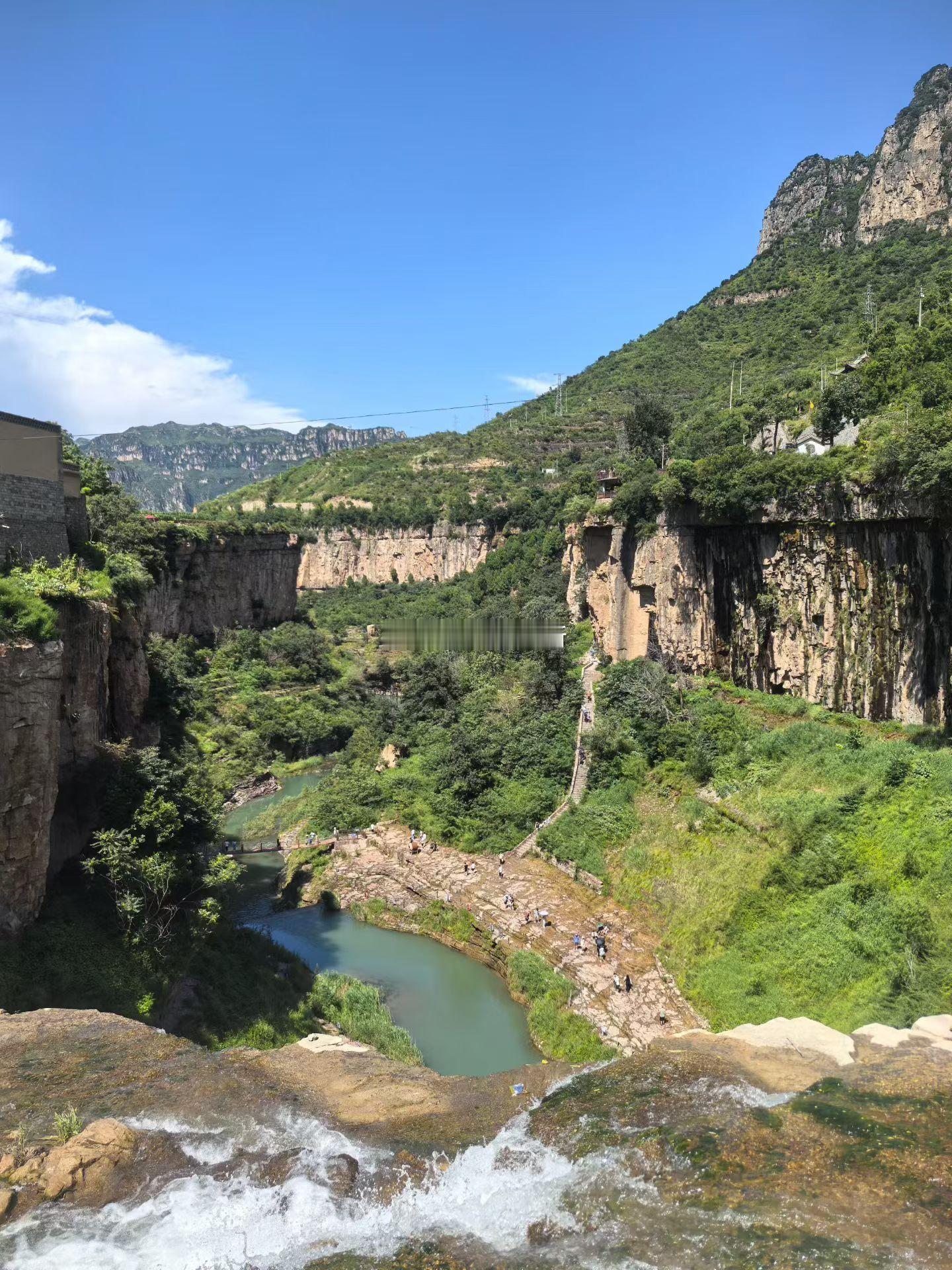 崖边俯瞰峡谷，清溪曲折流淌，层岩与浓绿相映，山野间藏着盛夏难得的静谧。