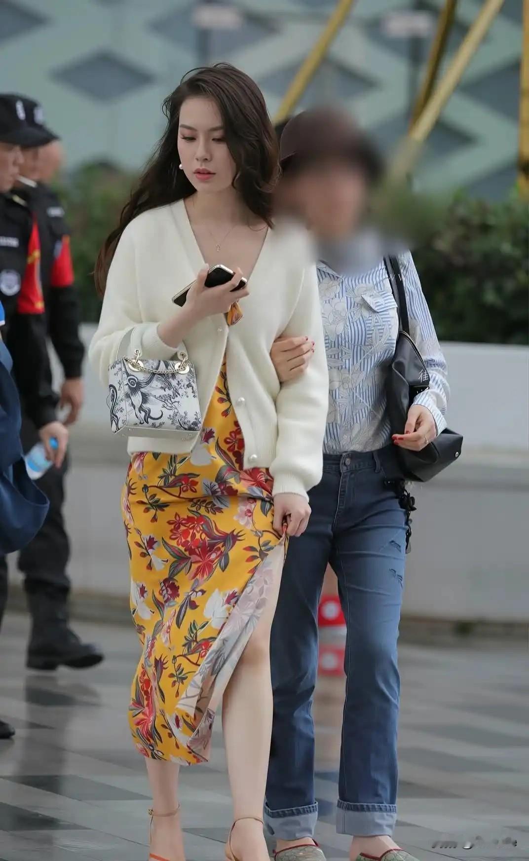 两个女孩在街上走着，一个穿裙子，一个穿牛仔裤。