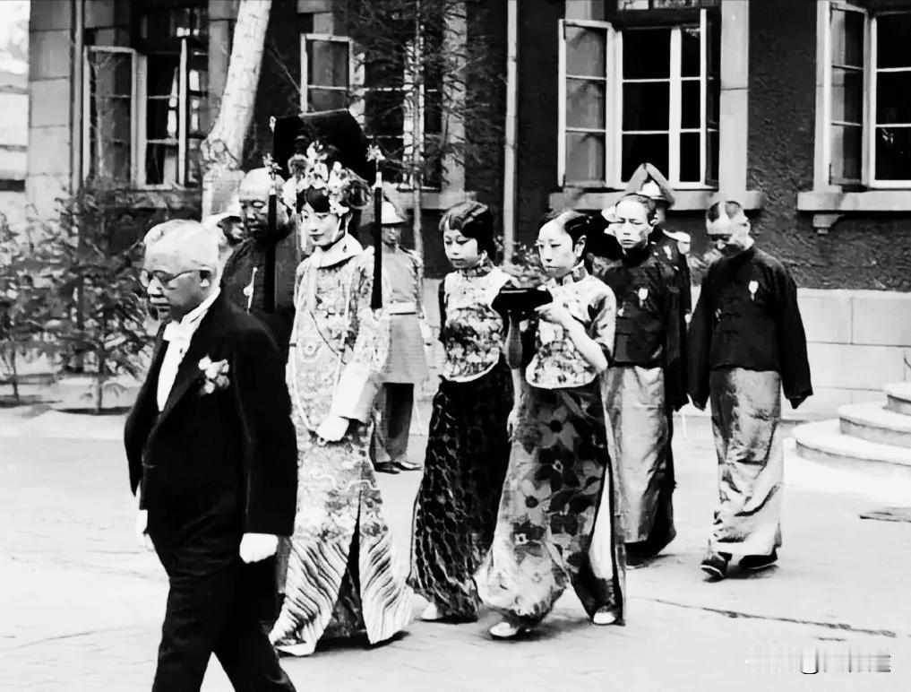 民国时期，在天津的婉容出行照片，依然穿着宫廷旗装，身边还是跟着太监、宫女等仆从，