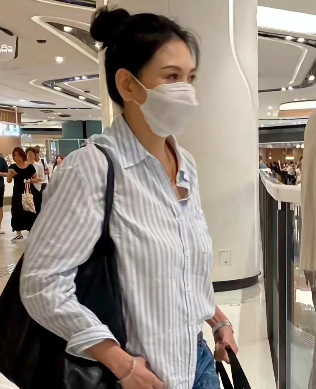 57岁邱淑贞在香港逛商场，她穿着条纹衬衫，扎着丸子头，虽然穿衣打扮低调，但身上的