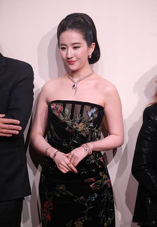 刘亦菲此次亮相，身着一袭黑色抹胸丝绒礼服，裙身上的花卉刺绣色彩雅致，复古丝绒的华