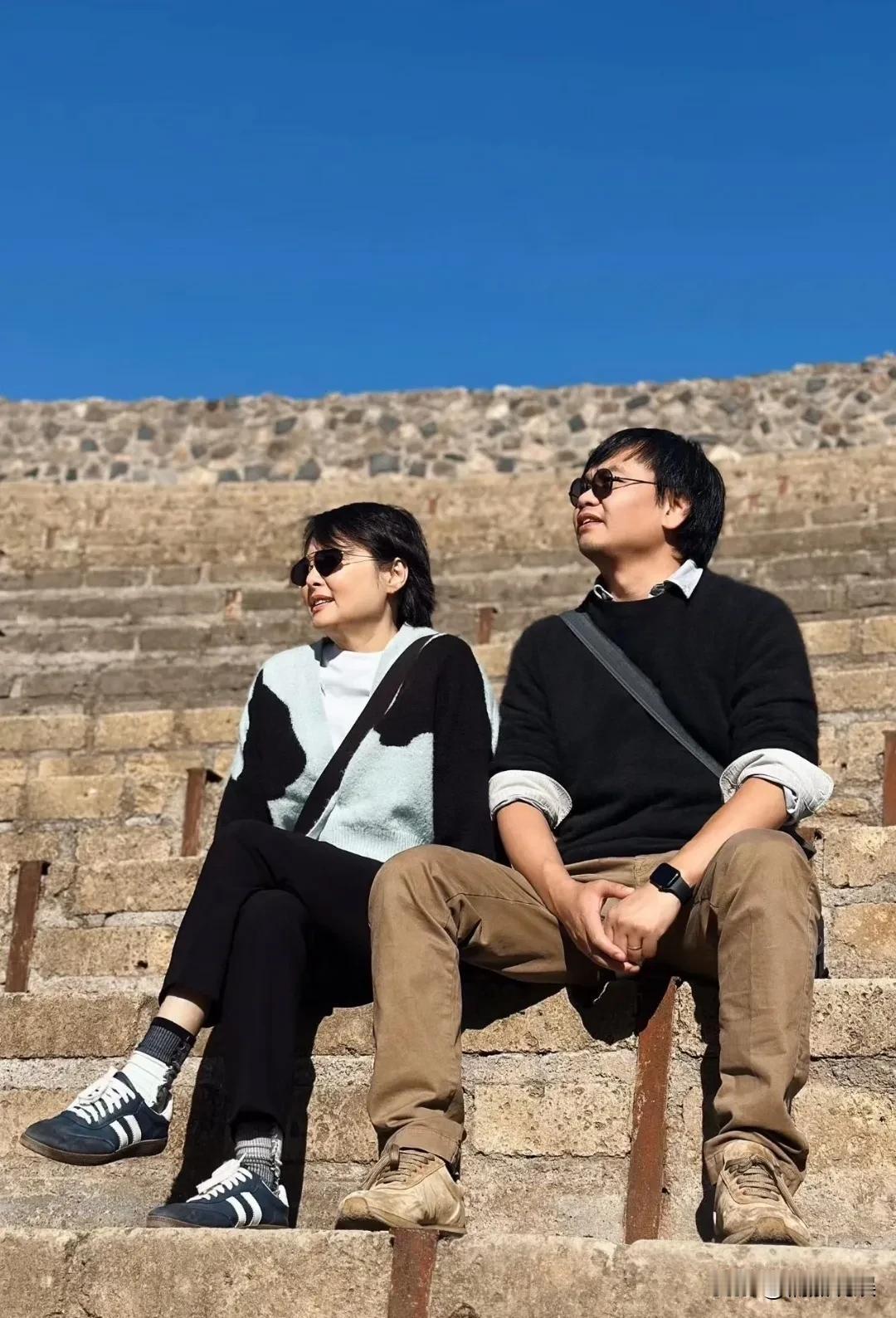 演员袁立夫妻俩现身国外旅游，夫妻俩坐在石台阶上，侧脸很有夫妻相。53岁的她，瘦