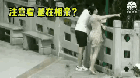 男士与相亲刚认识的女孩并排站立，在公园看着风景，有说有笑，男士玩顺势搂到她肩膀位