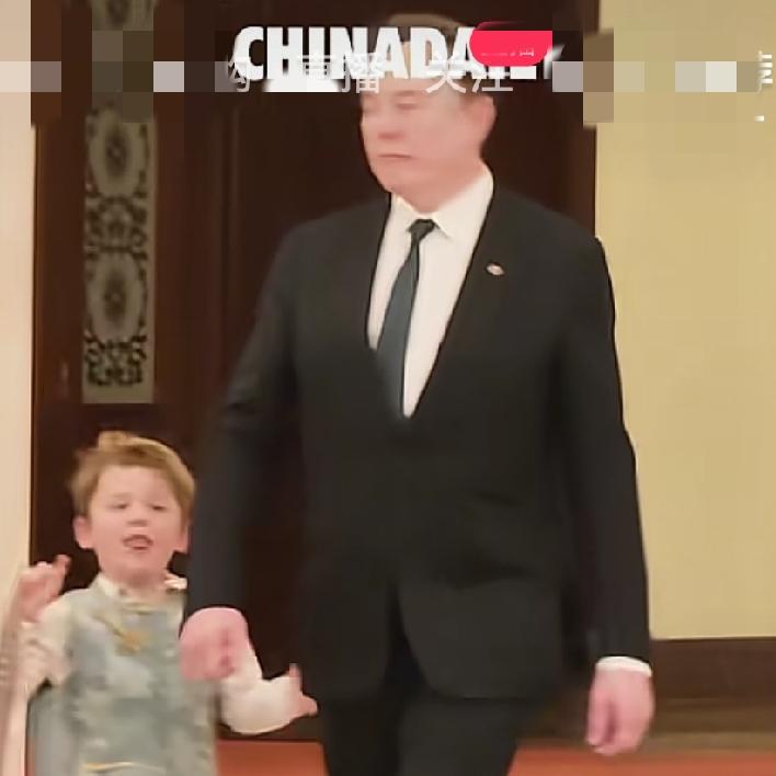 马斯克大步流星往前走，小儿子X连跑带颠在后面追，还要自己拎着玩偶背包，这就