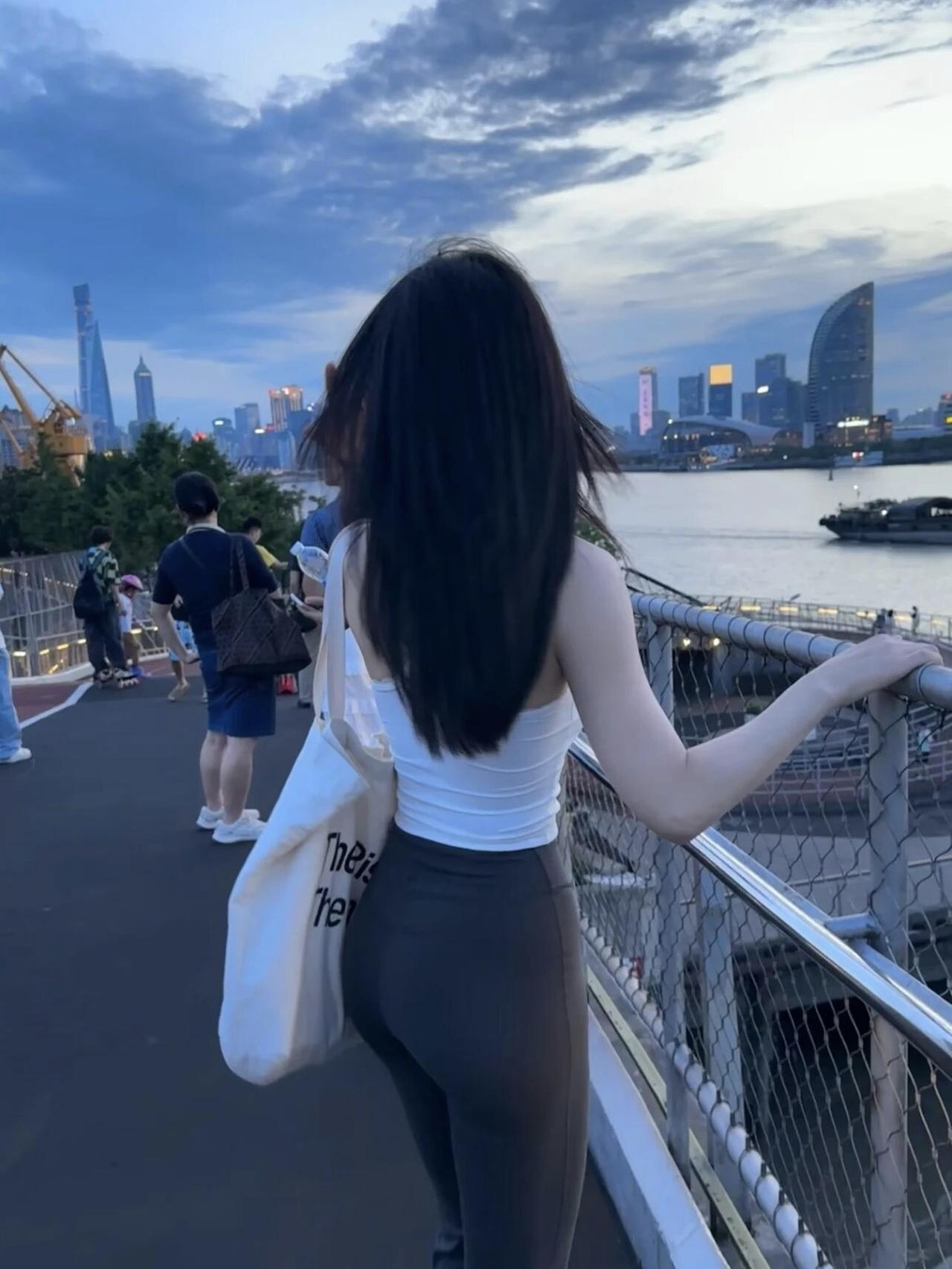 夕阳下，她靠在桥边欣赏风景。