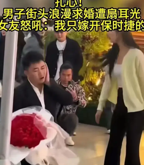 男子在大庭广众之下手捧鲜花双膝跪地向女友求婚。不料女友厌恶至极，反手“啪”一巴掌