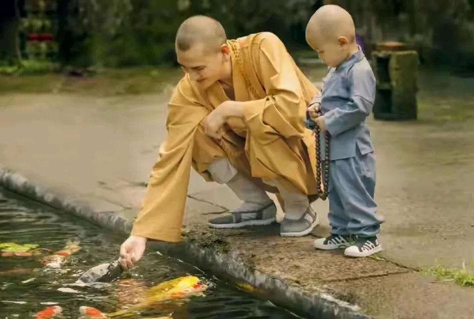 释明心身旁有位小和尚，这么小的孩子就出家了么？以后长大了他看到和释明心合影的女子