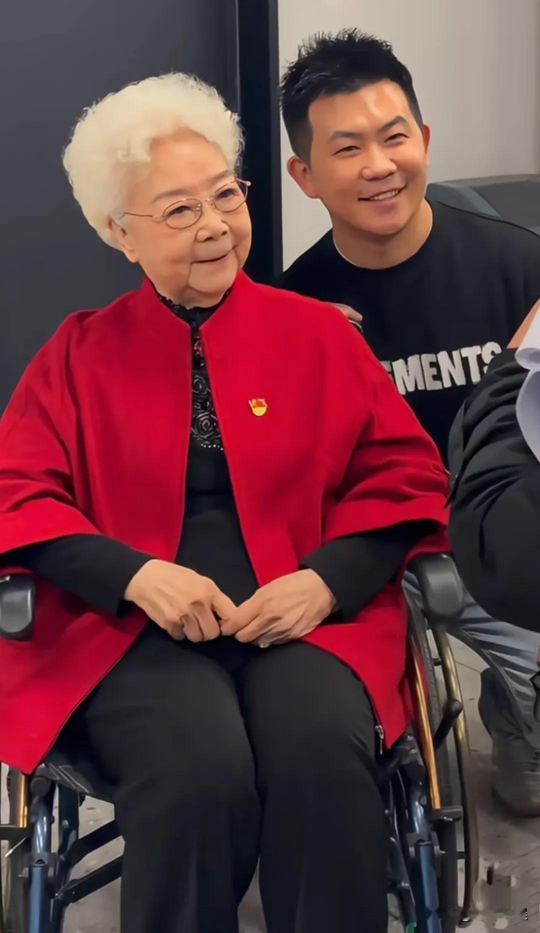 老艺术家田华老师参加活动，穿着一件大红色的外套，满头银发，戴着眼镜，气质斯文，有