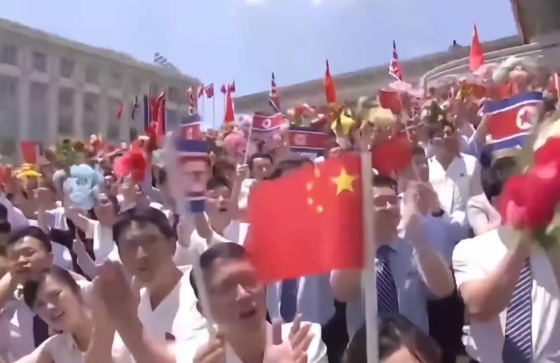 难得一见这样的镜头朝鲜民众着装统一，脸上洋溢着干净真诚的笑容，挥舞着中朝两国的