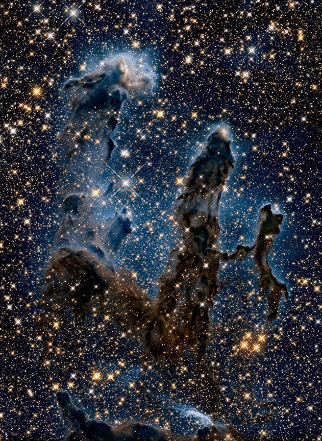 创生之柱，红外线拍摄到的光芒四射的年轻恒星穿过黑暗的尘埃和气体云。​​​
