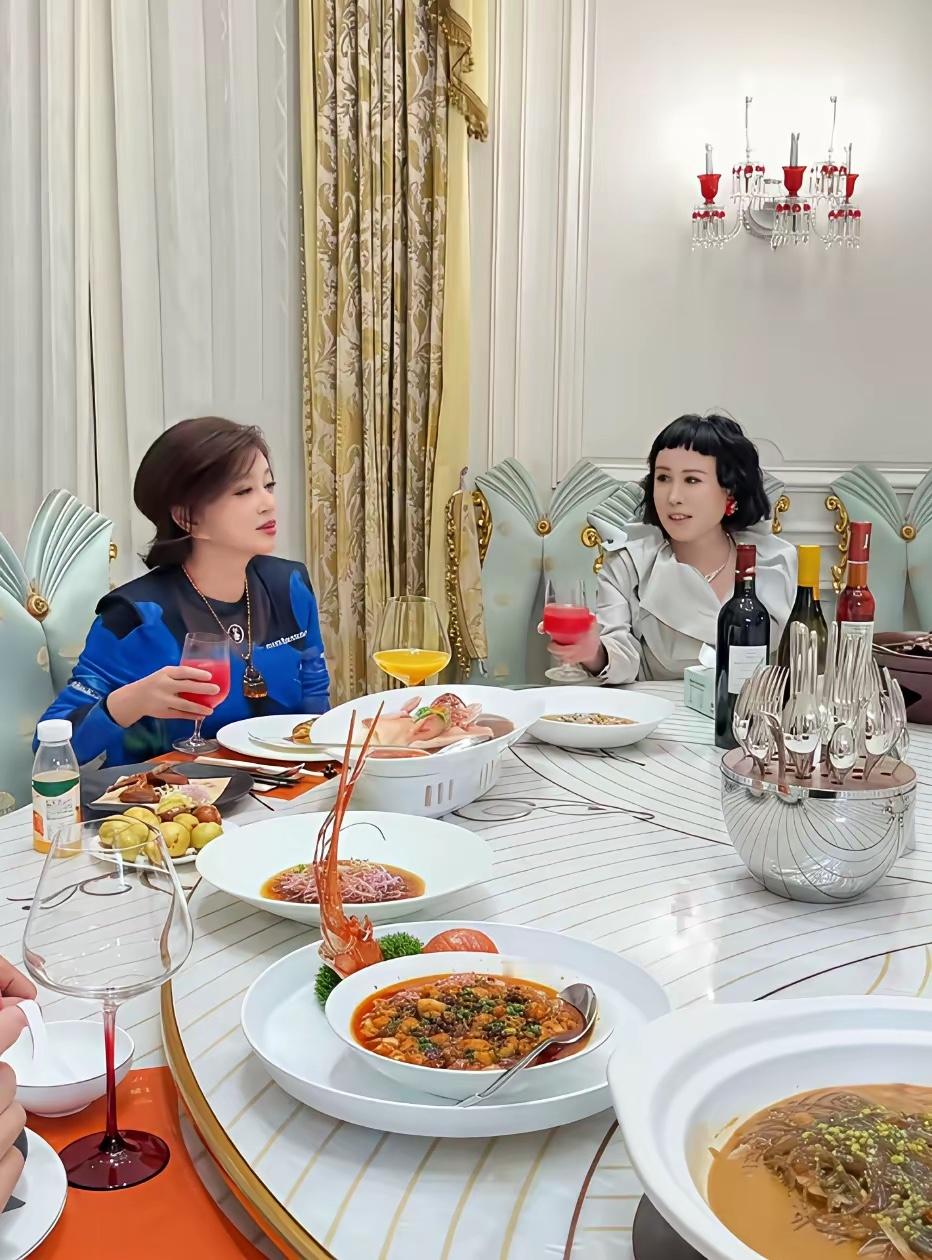 刘晓庆与友人聚餐时的一幕，餐桌上摆着大澳龙等各种高端食材，酒水更是双鸡+拉菲。