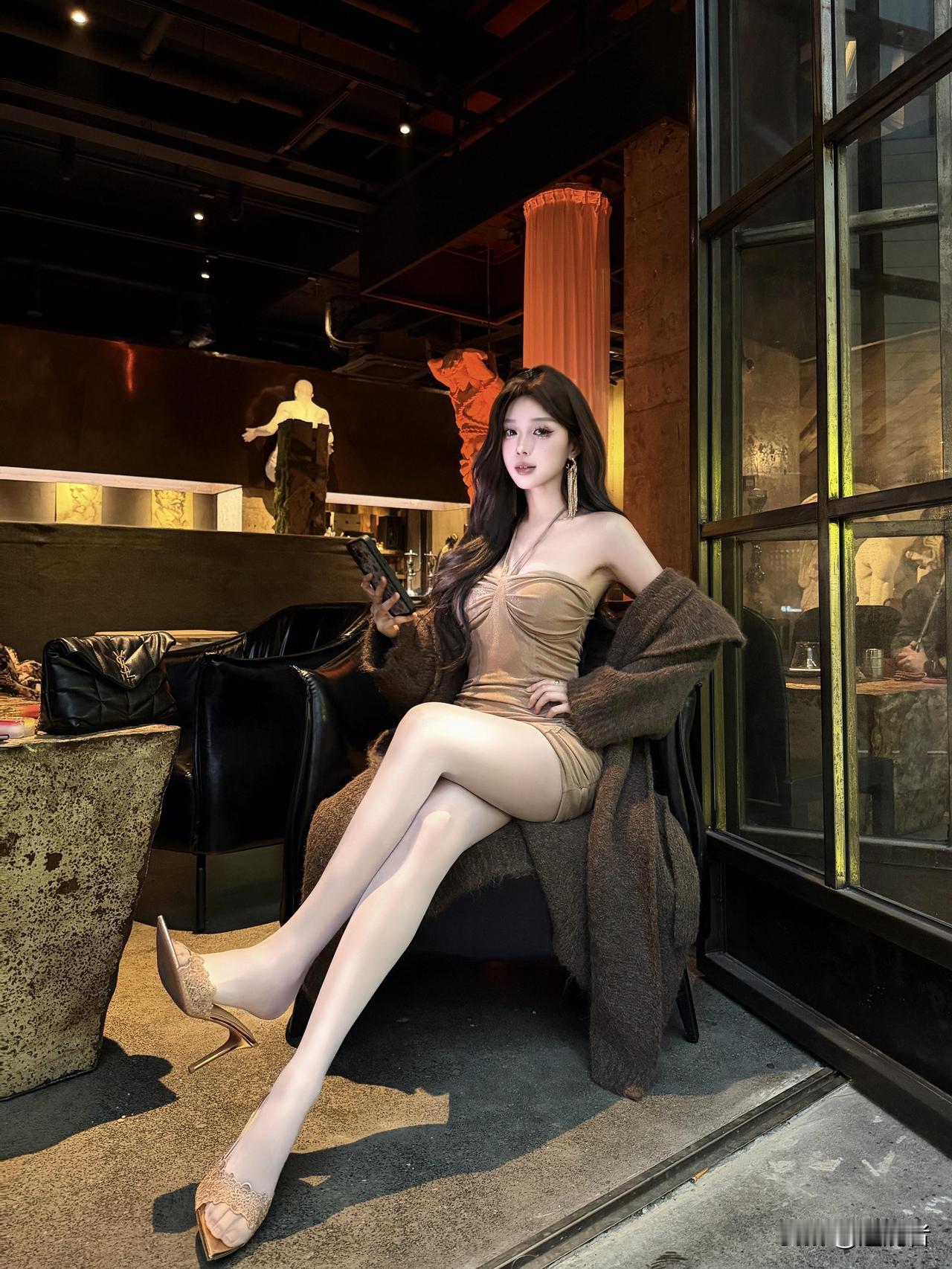画面中，少女身着焦糖色抹胸紧身短裙，搭配深棕色慵懒开衫，整体造型温柔又性感。抹胸