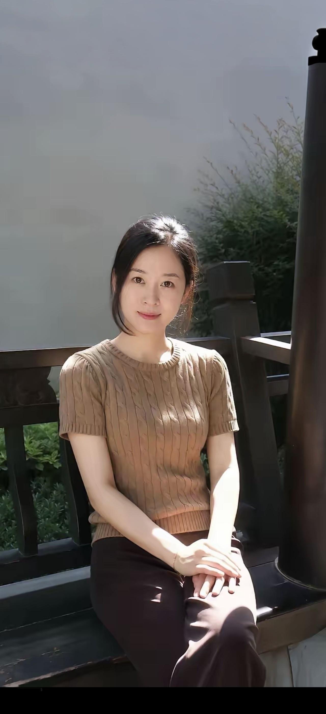 阳光明媚，她坐在长椅上。
