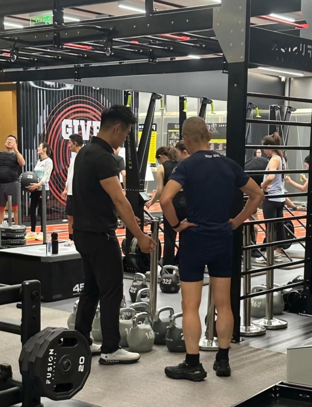 王石现身健身房锻练肌肉，他一会练举重，一会练拉伸，还认真听取教练安排，每个动作做