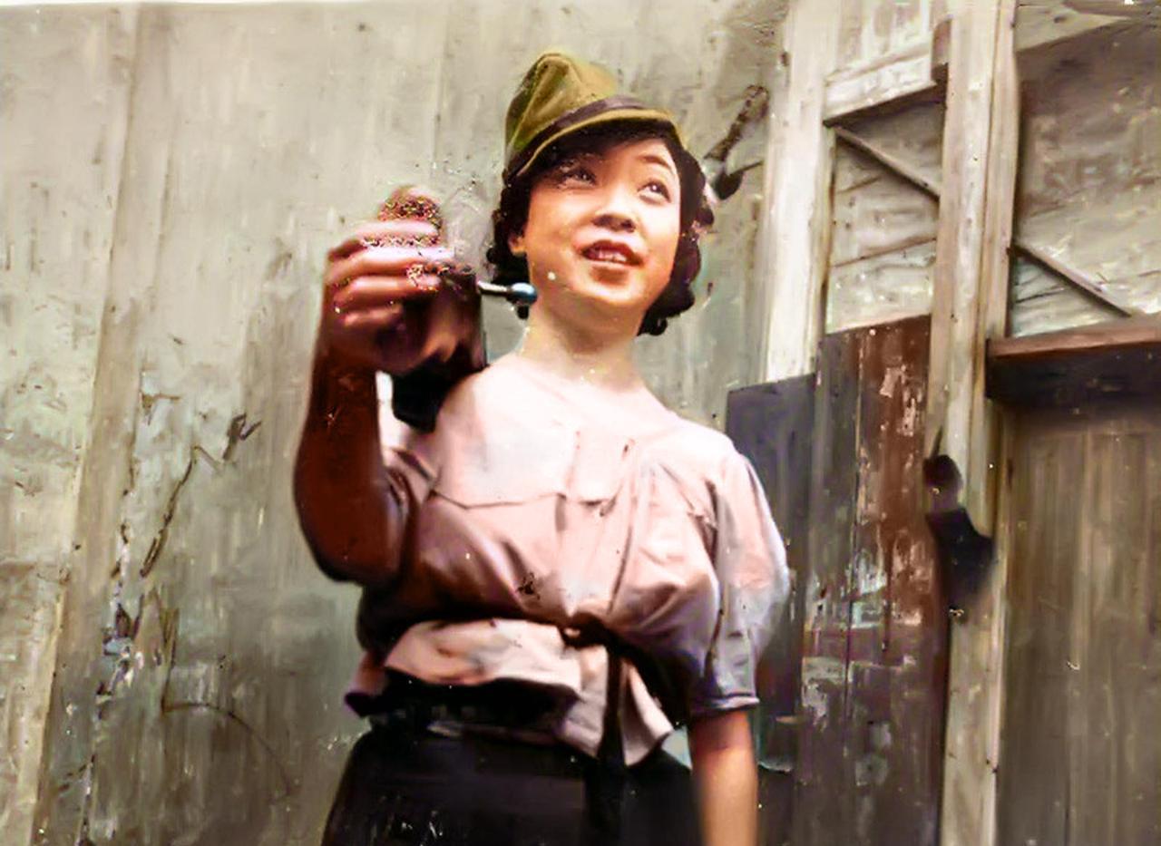 1939年，广西南宁。一个年轻漂亮的女子，头戴日军帽子，肩扛着三八步枪，面带笑容