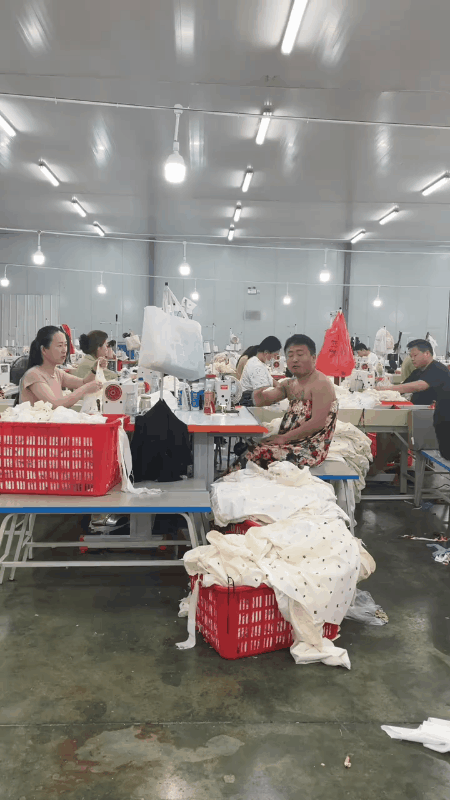 这位在服装厂工作的大哥怎么身上穿了一件花裙子啊？这可把旁边的女同事给看笑了！