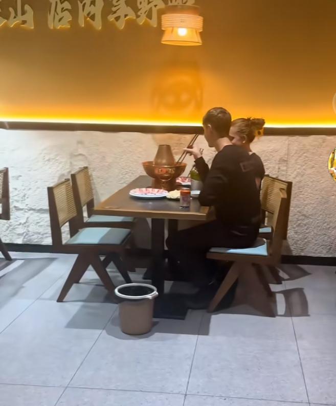 两个外国小孩在中国吃火锅，但是由于没有吃过，两个人对着锅很迷茫，这时候一个女子看
