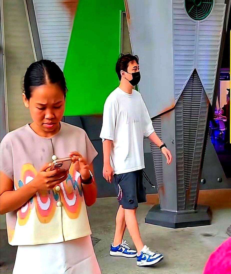 他在新加坡街头弯腰驼背，穿着松垮的大裤衩，手里还拎着一个极不协调的粉色女包。如果