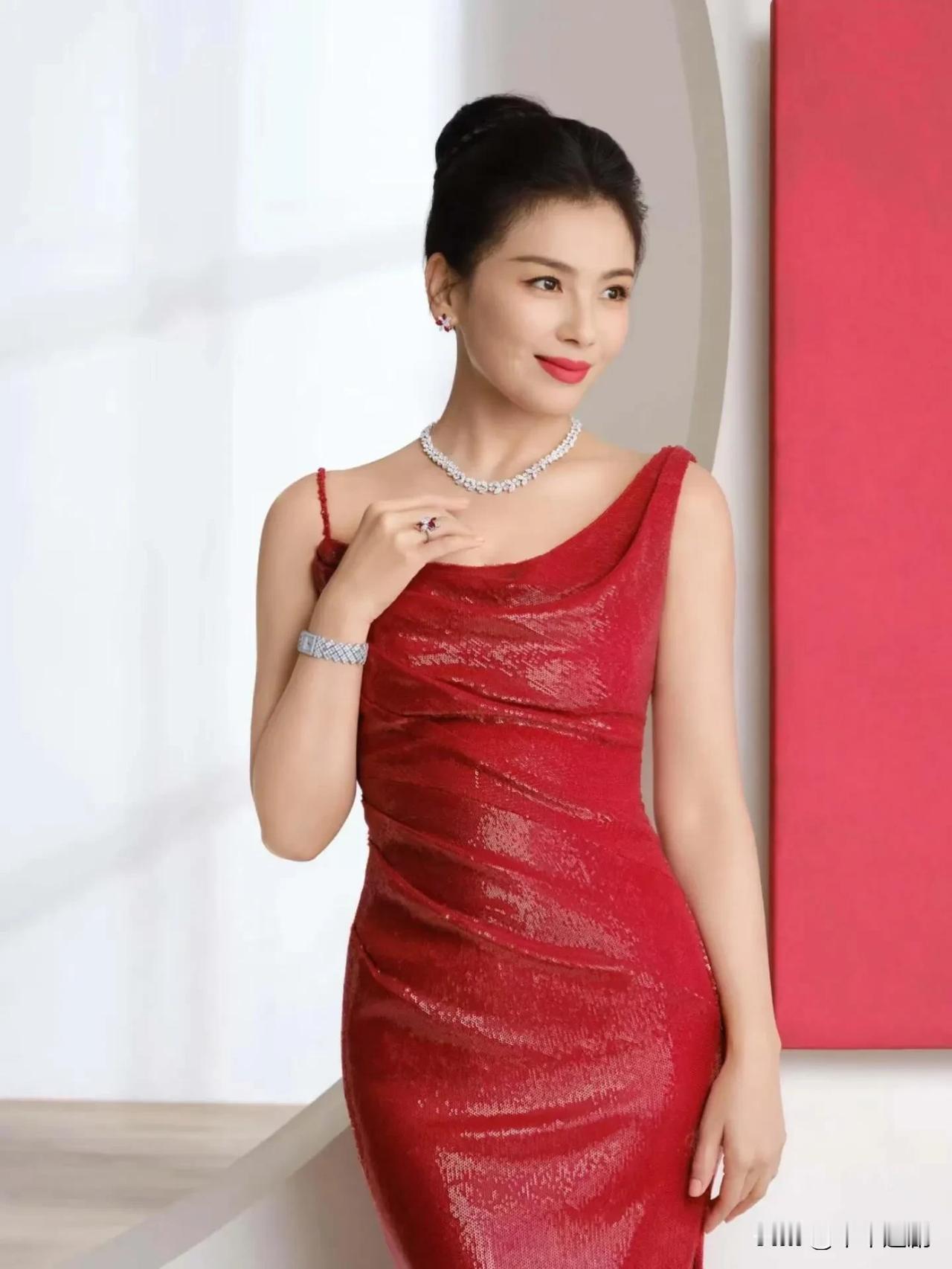 一袭红丝绒礼服裹着明艳气场，碎钻珠宝点缀颈间腕间，在红白撞色的空间里，演绎成熟女