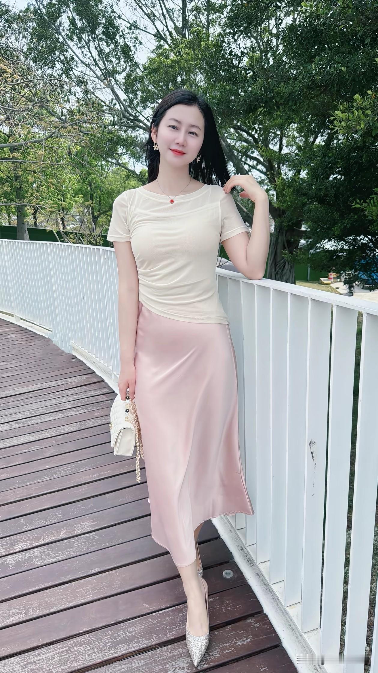 在春日的午后，漫步于木栈道，微风轻拂发丝。米杏色网纱上衣勾勒温柔，藕粉色缎面半裙