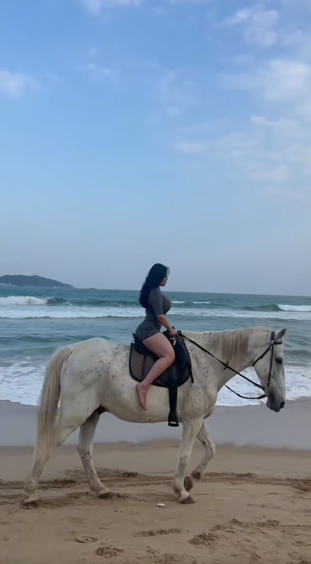骑在马背上，迎着海风漫步在沙滩上。