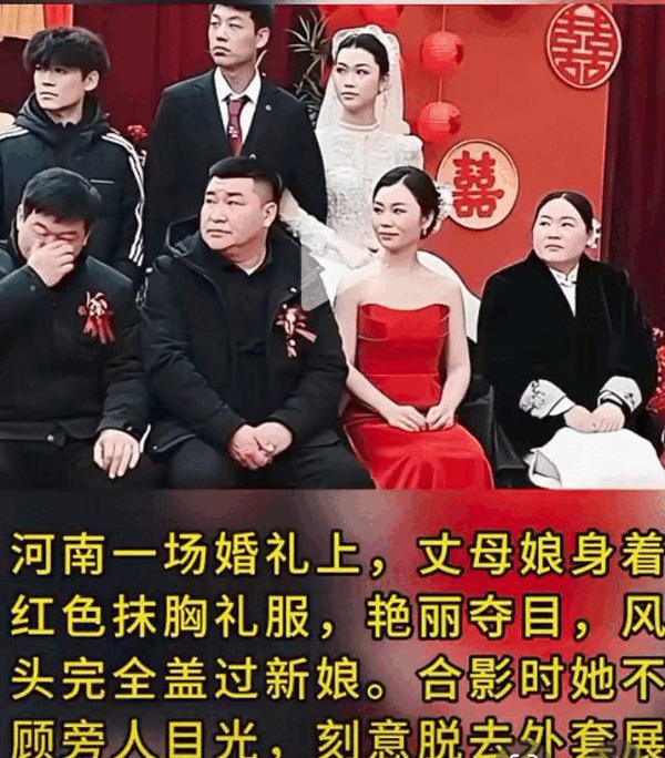 河南，一丈母娘居然穿红抹胸霸着C位还拎空包凹造型，新郎劝都劝不住，而大冬天宾客都