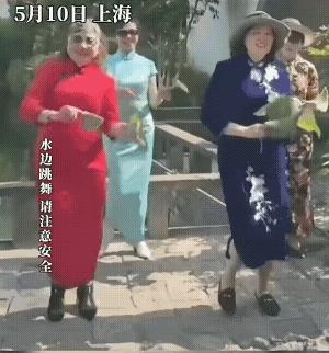 公园里四位大妈跟着音乐跳舞，穿的都是旗袍，每位大妈旗袍的颜色各不相同，人手拿着一