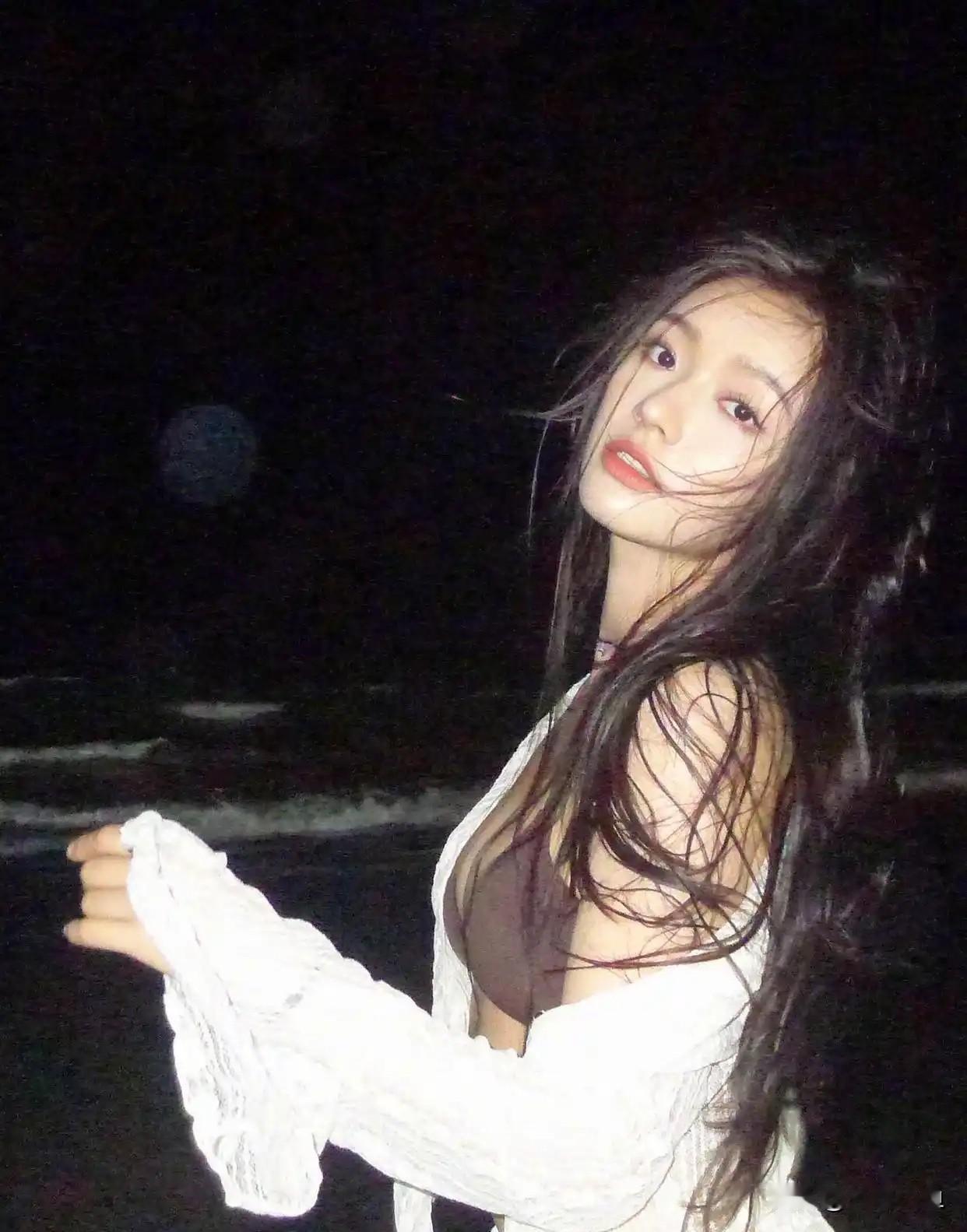 林允夜色海边氛围感大片！一身深棕色吊带内搭，外搭米白色镂空针织开衫，同系列半