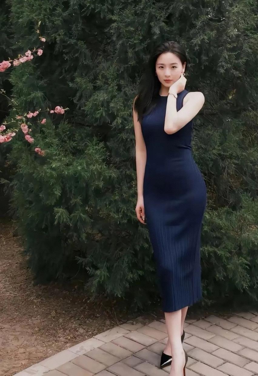 藏蓝裙裹着春的软，树影里漫出轻熟的雅，连枝上的粉花都沾了点温柔气场。