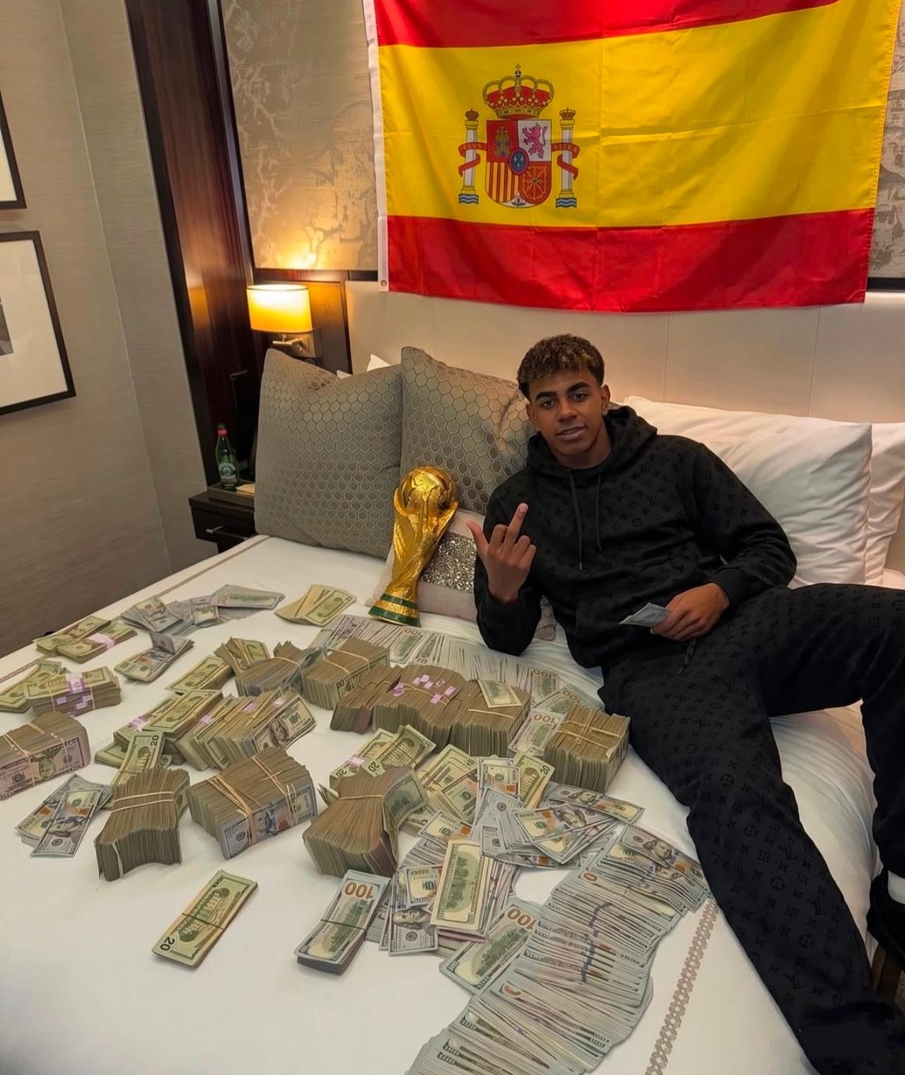 哇塞，镜头中身穿黑色连帽卫衣的超级巨星亚马尔正坐在铺满成捆美元现金的床上，面带微