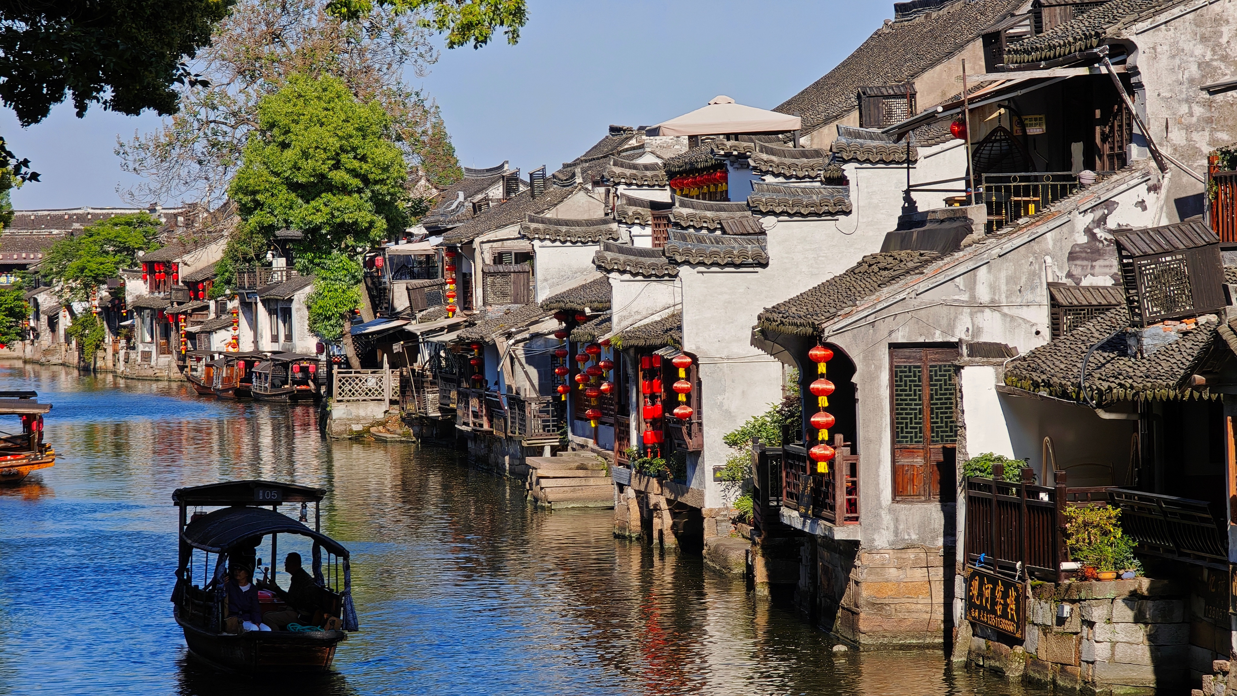 日光漫过白墙，河水沿街巷流淌。乌篷船破开水面的波光，穿过石拱桥的拱洞。临水老屋一