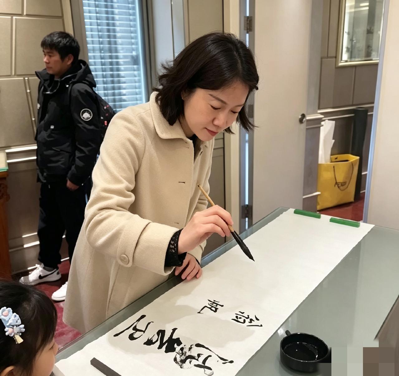 现场看翁帆写毛笔字，字迹清雅耐看。一旁的小女孩静静围观看得专注，她待人平和从容，