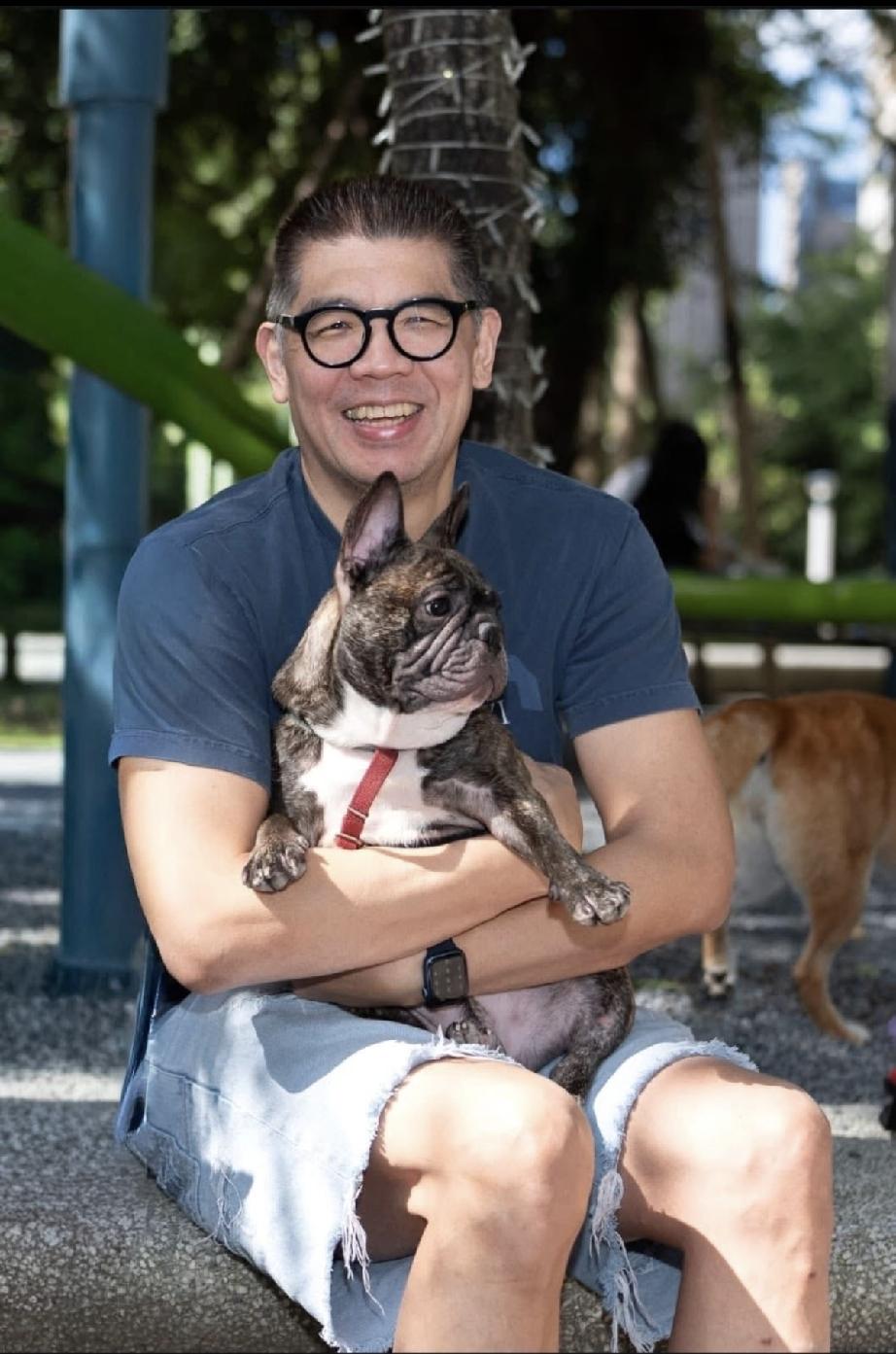 抱着狗狗的连胜文可开心了，他怀里狗狗的表情奶凶奶凶的；连胜文的身材很魁梧，衬托