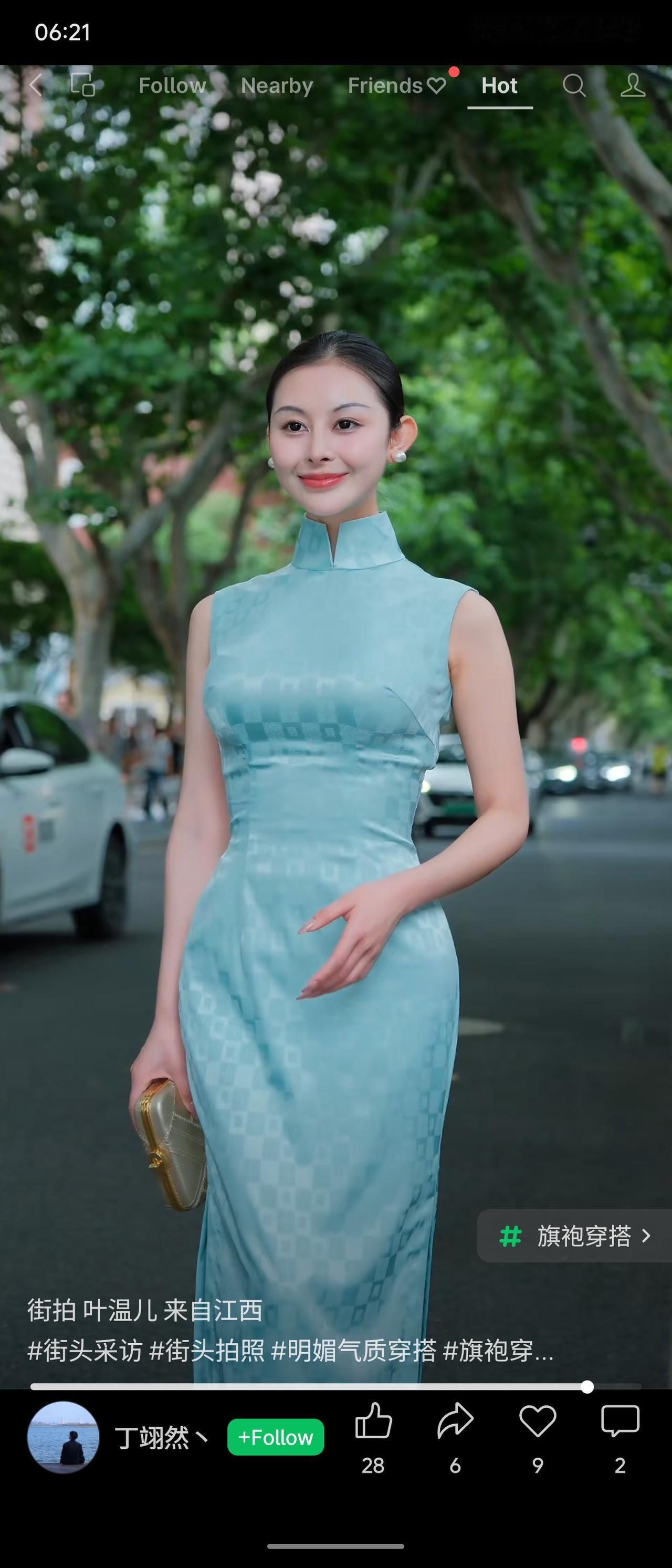 梧桐街道下的旗袍街拍，女子梳利落盘发，身着浅蓝暗格无袖旗袍，手拿精致金边手包。面