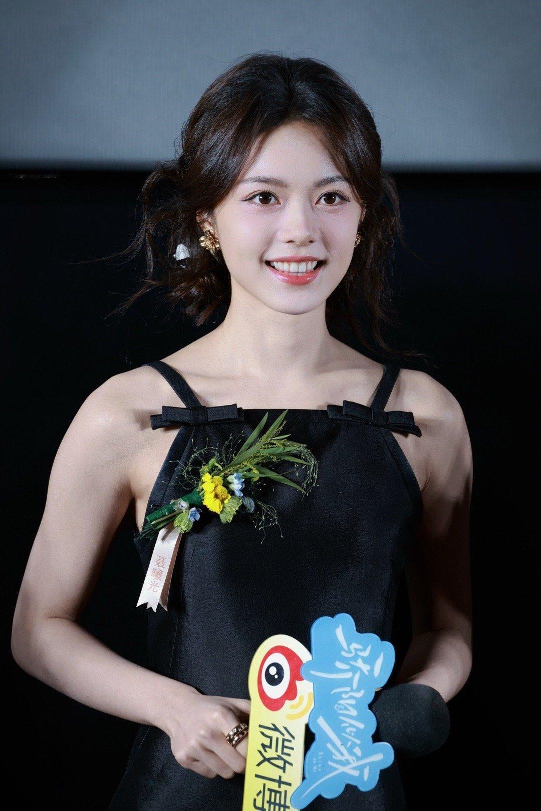 赵今麦藏青色吊带裙衬得肌肤莹白，碎发微卷勾勒清甜轮廓，手持手牌站在台前，一举一