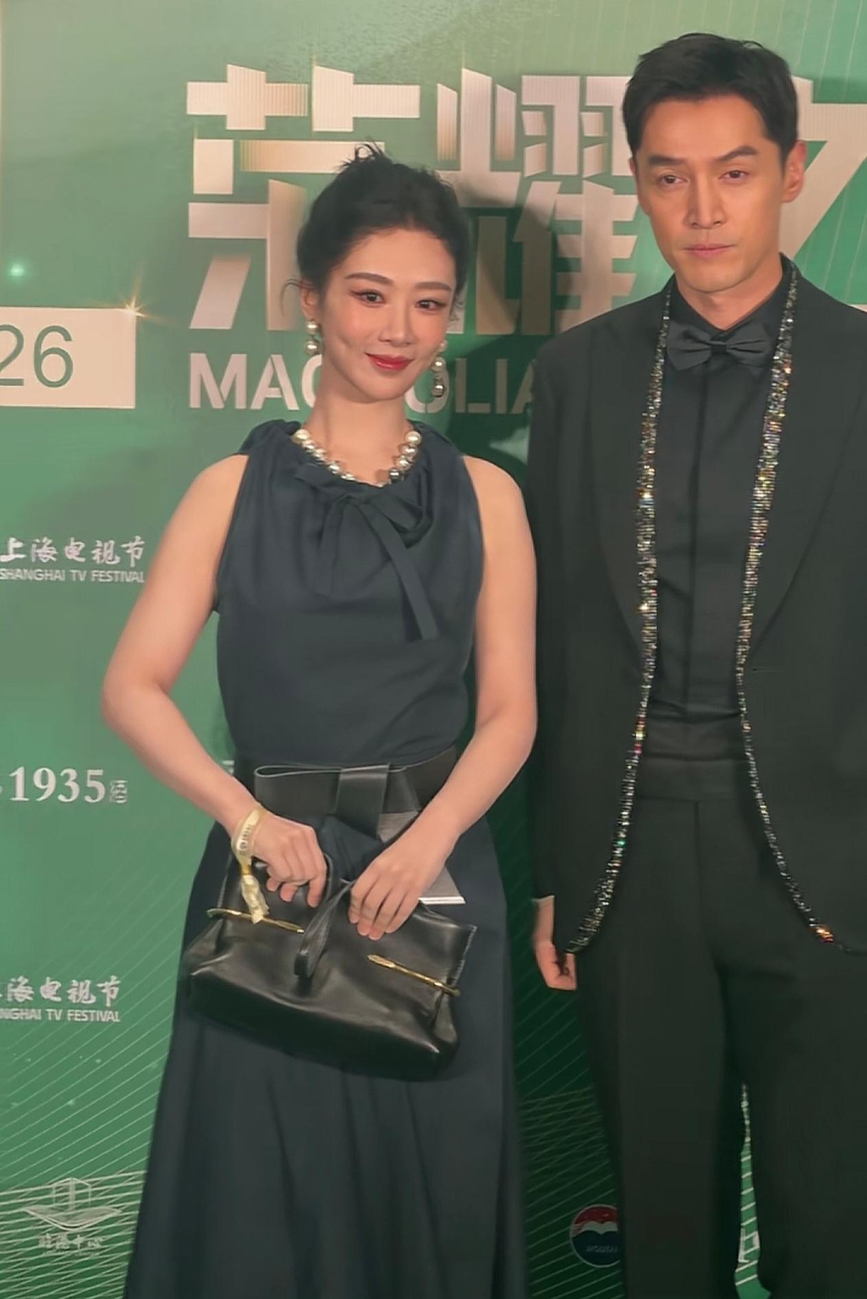6月25日白玉兰提名晚宴，杨紫胡歌同框出镜。杨紫藏蓝缎面长裙配珍珠配饰，笑起
