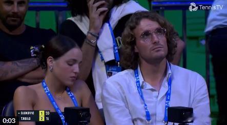 临时退出雅典比赛的西西帕斯在观众席观看了德约的首场比赛。身边还坐着一位美女。在和