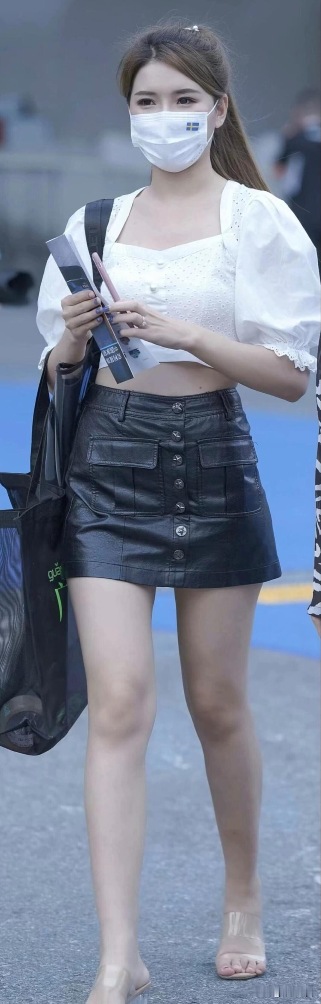 街头偶遇时尚女孩，白色上衣配黑色皮裙，简约又时髦，尽显青春活力。