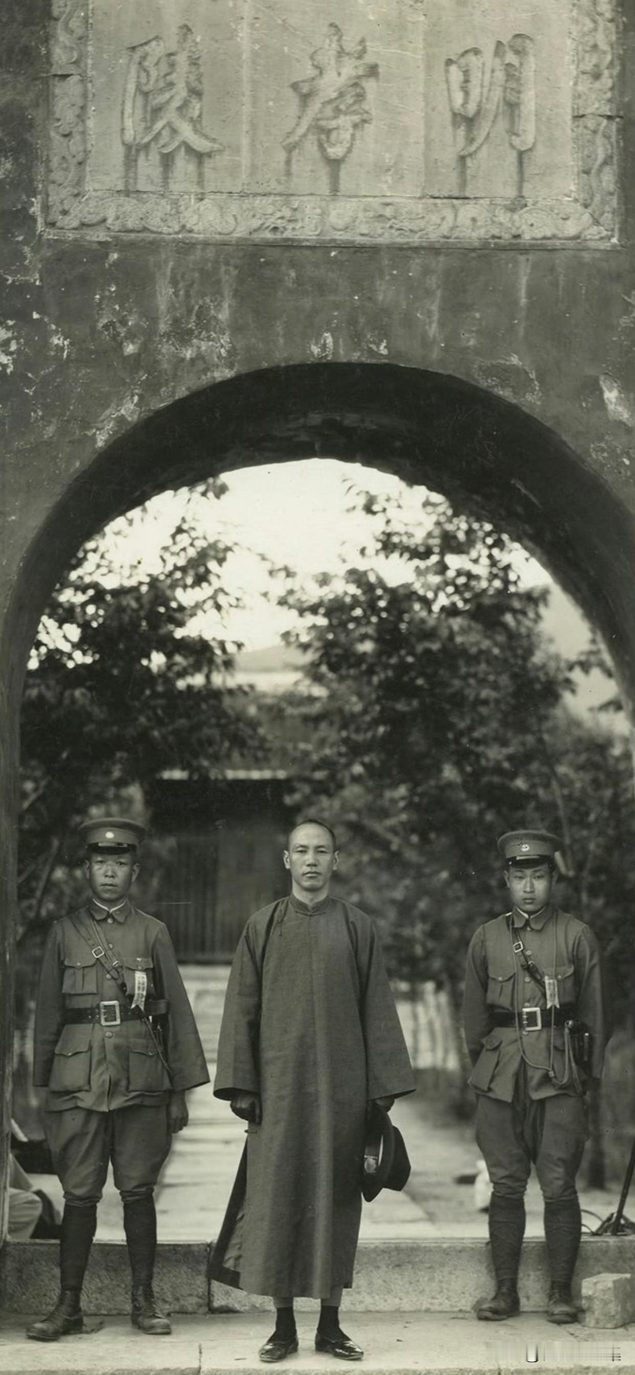 1927年，蒋介石身着棕色长衫马褂，身形消瘦，神情严肃地站在明孝陵拱门前留影。在