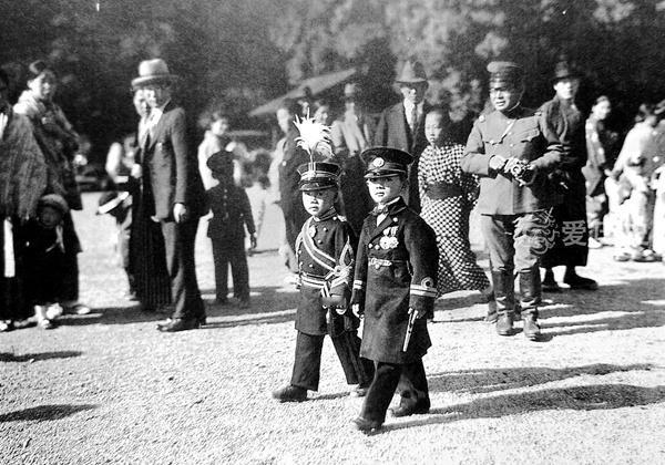 看这张图，两个日本儿童，身穿军服，昂头挺胸地走在街头，仿佛马上就要接受战场的洗礼