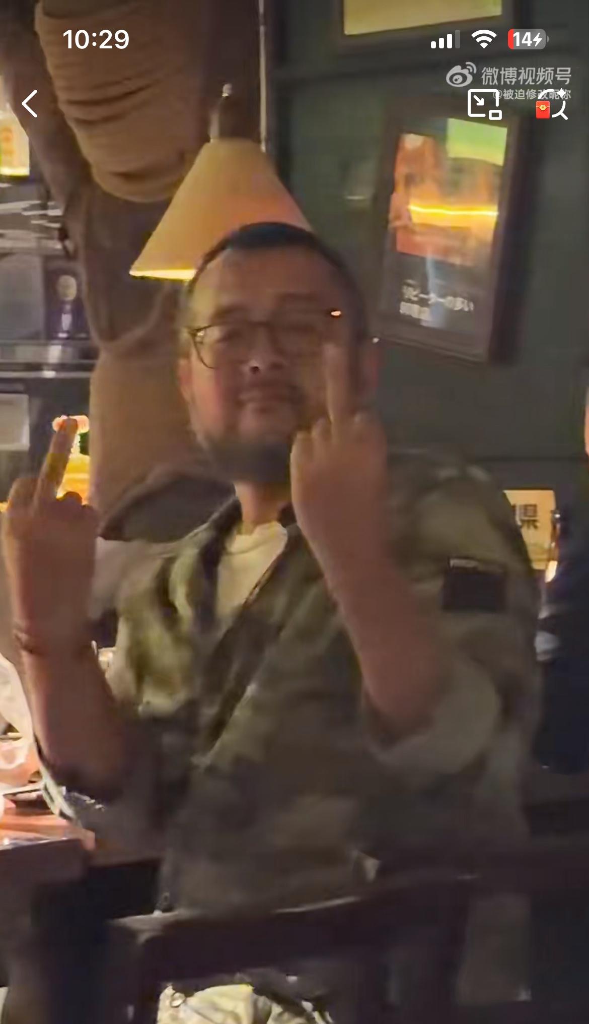 图中的男子想邀请邻桌的女孩一起喝酒，遭到女孩的嘲笑，男子竖中指发泄不满。没想到男