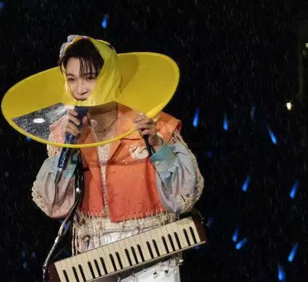 为了减少大雨对琴的音质的影响，他戴起了雨帽（估且这么叫吧），真的忍不住笑啊！好可