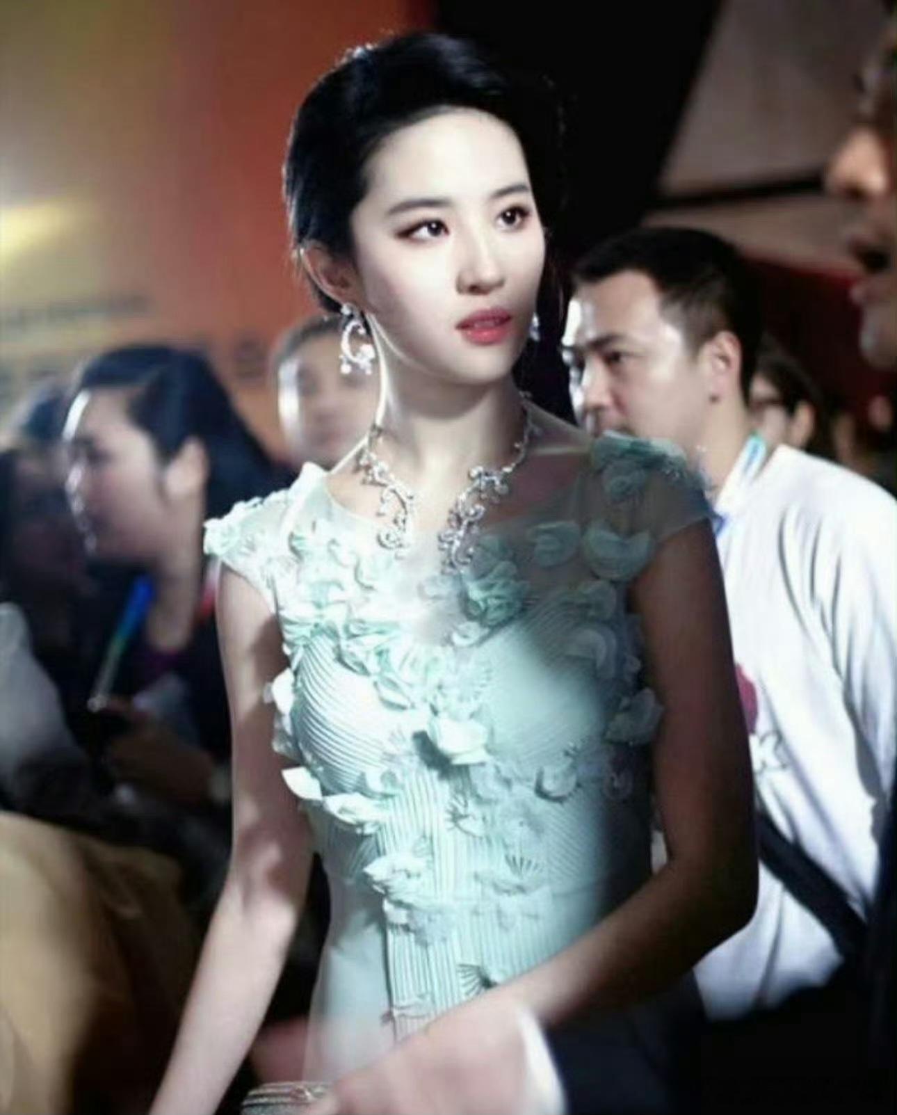 刘亦菲身着一袭薄荷绿立体花朵礼裙，裙身细腻压褶，层叠花瓣从肩部蔓延至裙身，浪漫又