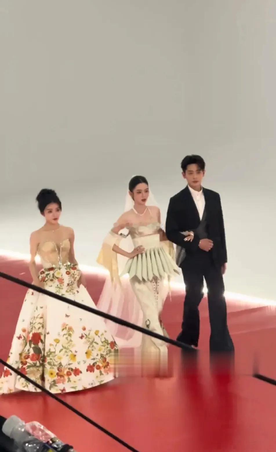 周也旁边的女生有点惨，裙摆又沉又大，只能自己提着，丞磊只顾扶着周也，两人有说有笑