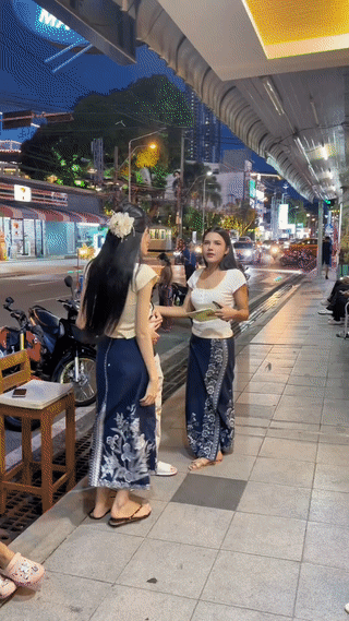 一名中国小伙在泰国🇹🇭街头和两名当地女子站在一起合影。小伙看起来还有点害羞