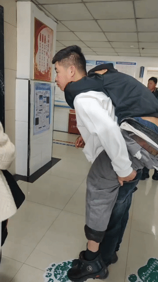 医院拍到的感人一幕。一名年轻男子背着一位患病的老人站在电梯口等电梯。但是他们