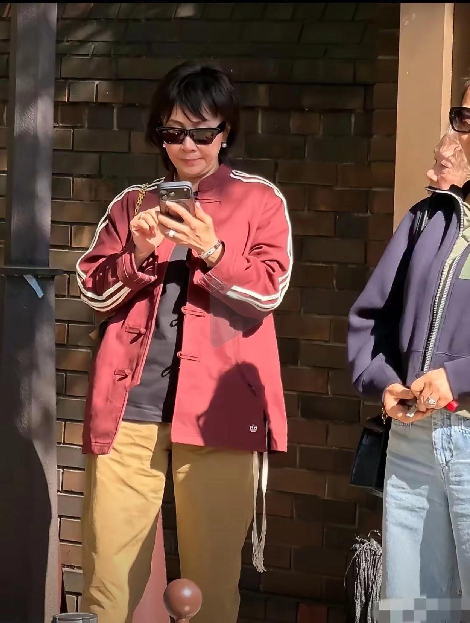 刘嘉玲东京亮相，新发型更显自然。她身着酒红色中式上衣与黄色休闲裤，搭配随性时髦，